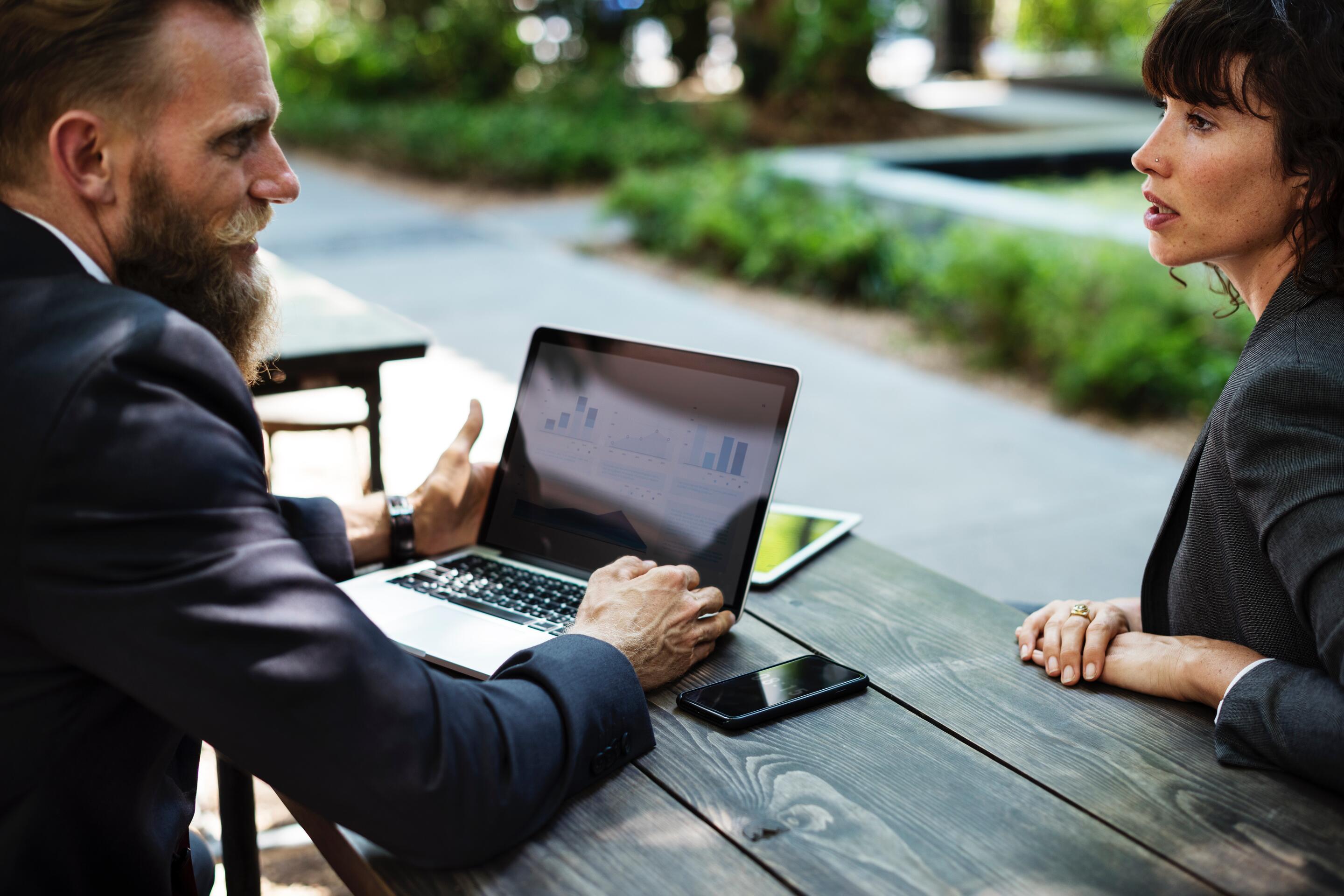 Man on laptop talking to woman